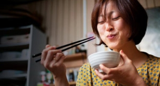 Woman eating from a bowl with chopsticks